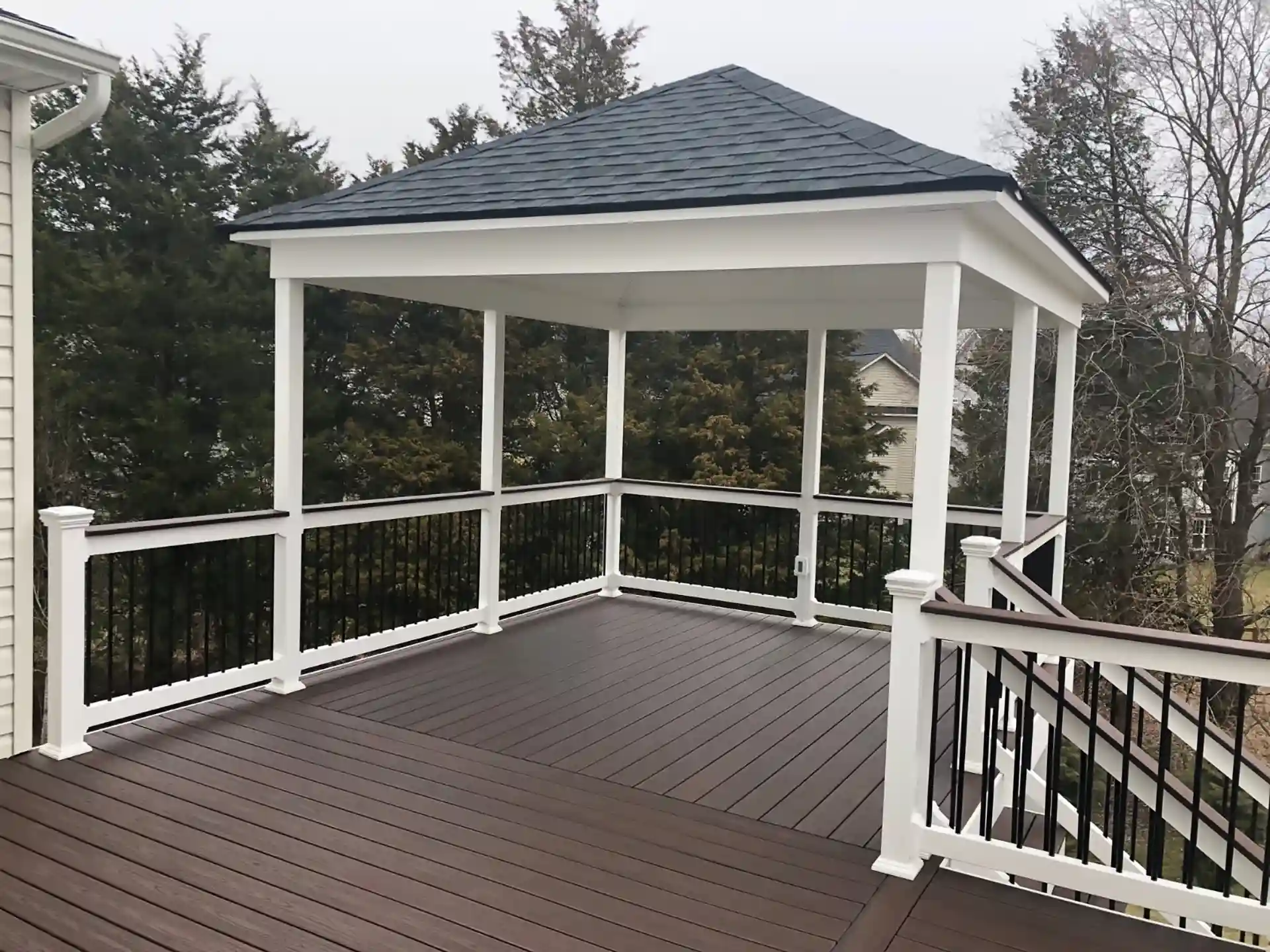 Photo of covered upper deck section with composite flooring, black spindles, and forest view.
